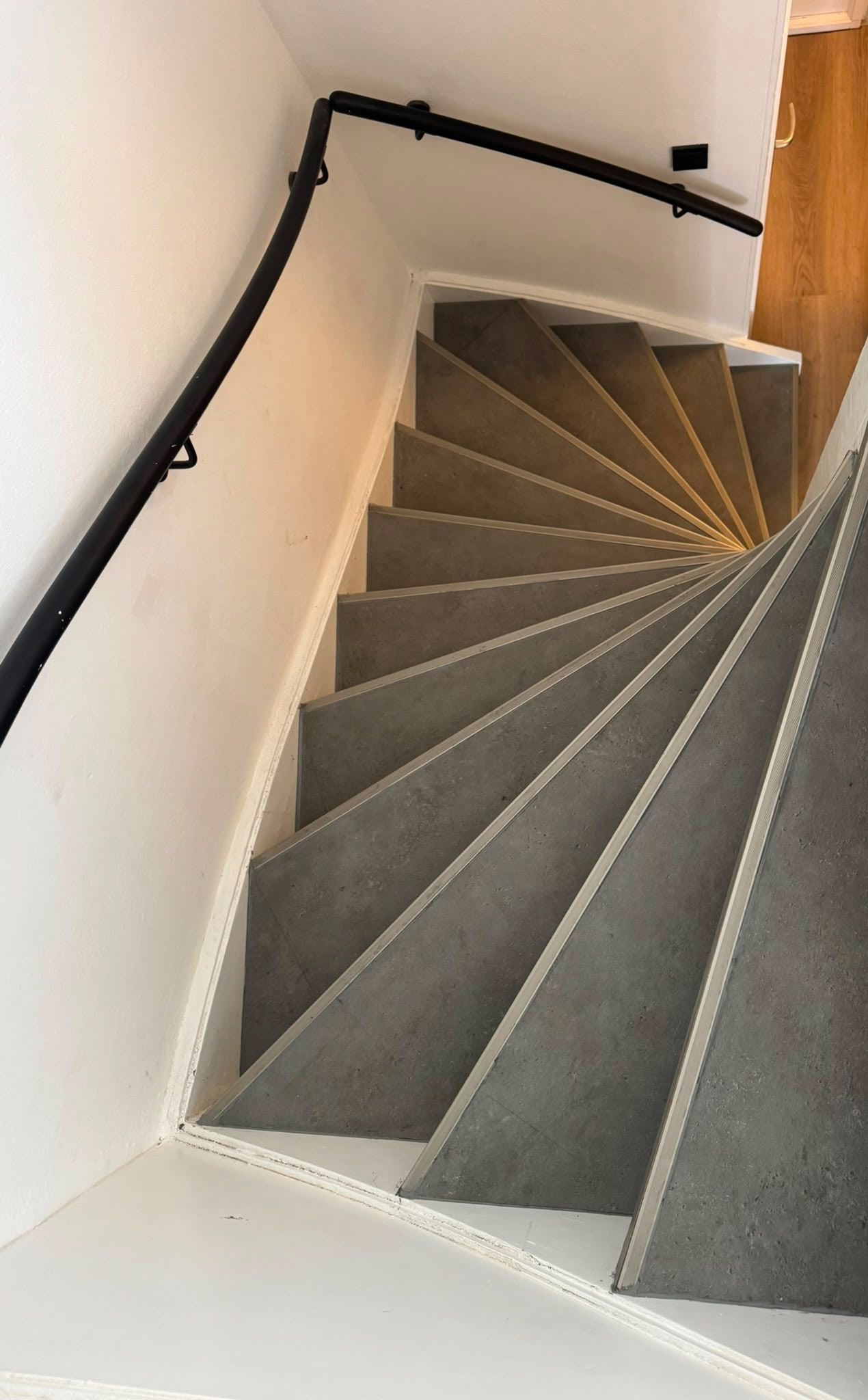 Draaitrap bekleed met grijze betonlook treden en aluminium trapneuzen