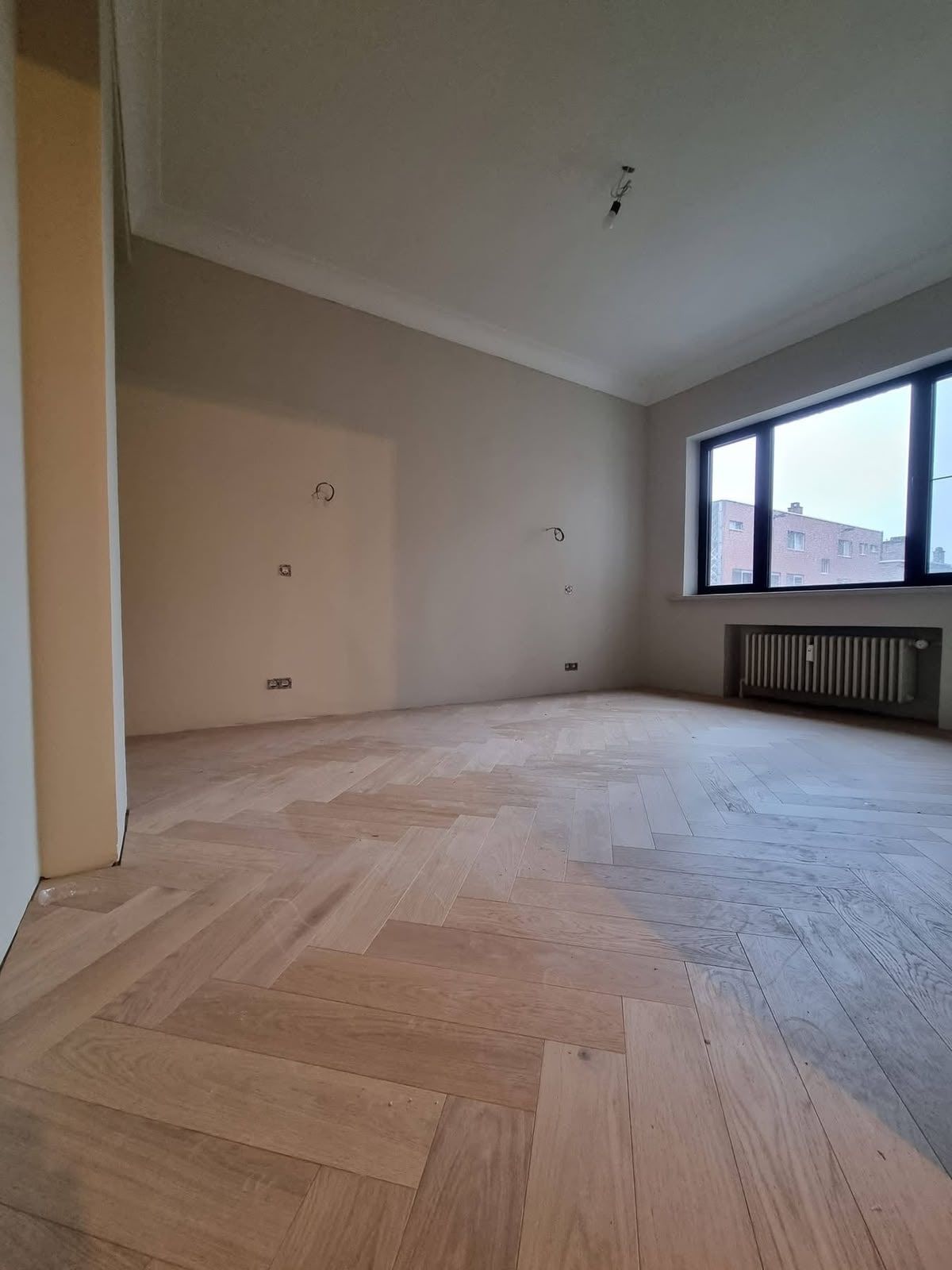 Licht eiken parket in visgraatpatroon in een lichte kamer met groot raam
