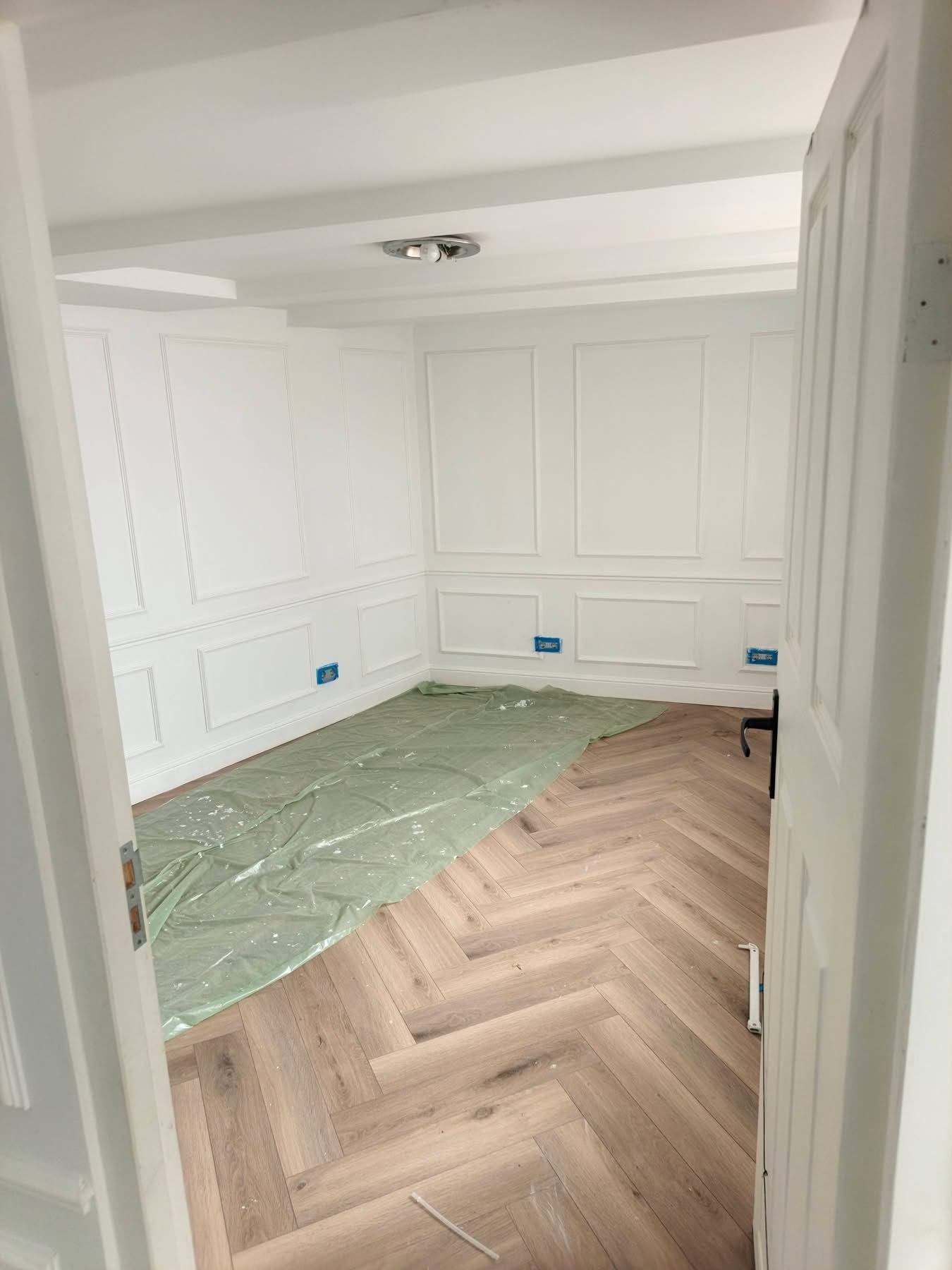 Kamer met witte wandlijsten rondom en een nieuwe visgraatvloer